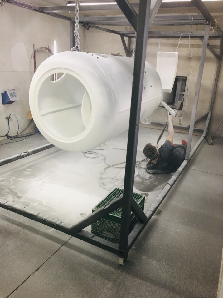 A large white industrial pipe fitting inside a metal frame in a workshop.