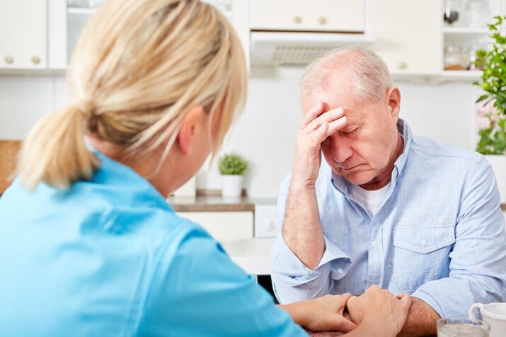 A doctor comforting a worried elderly man in a consultation.