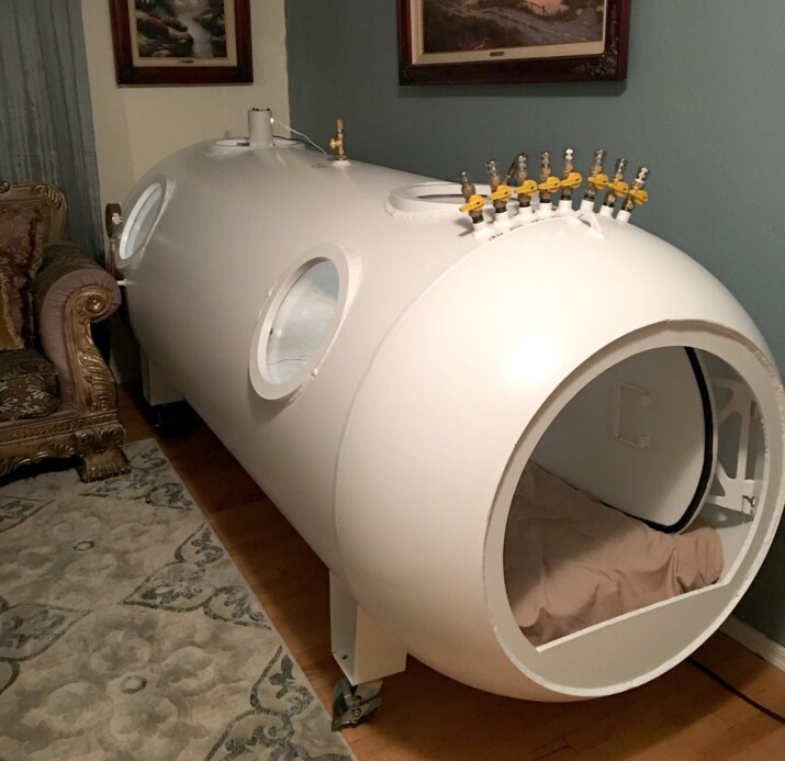 A large white cylindrical hyperbaric chamber with a round opening.