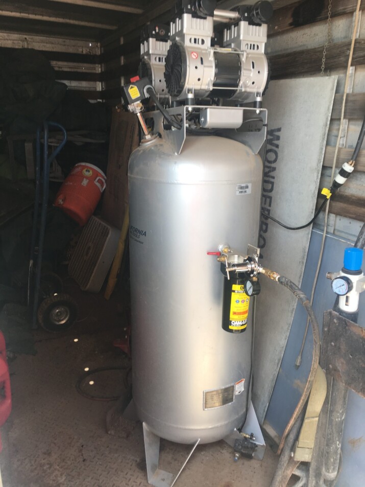 A large silver industrial tank with attached hoses and gauges.