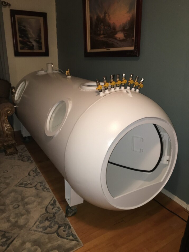 A white hyperbaric oxygen therapy chamber in a room.