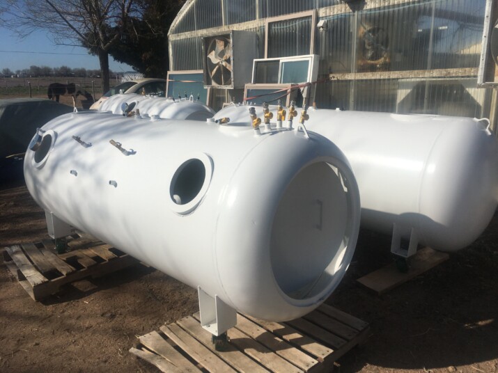 White industrial cylindrical tank with ports and fittings outdoors.