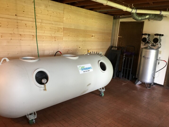 A large white cylindrical tank inside a room with wooden walls.