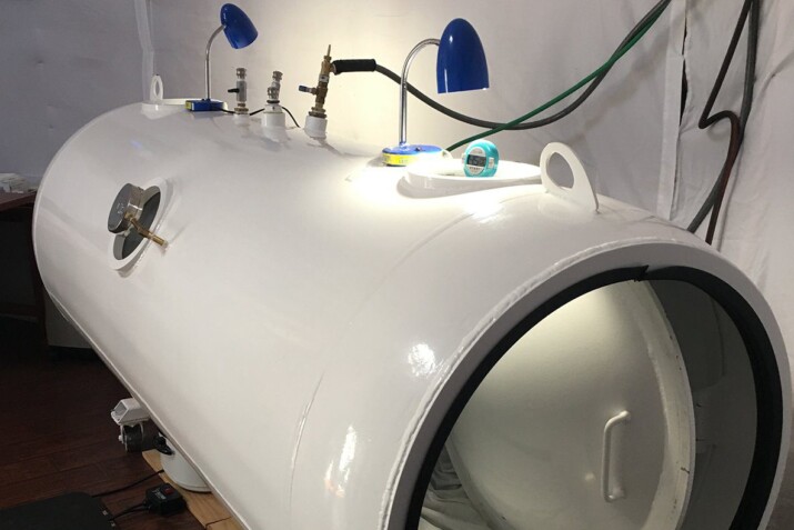Close-up of a white hyperbaric chamber with attached lamps and equipment.
