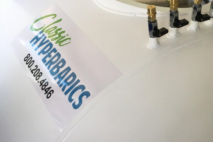 A white water tank labeled 'Classic Hyperbarics' with a pressure gauge and valve.